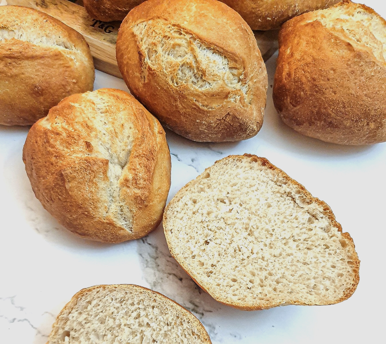 A crusty German bread roll cut in half to show the inside.