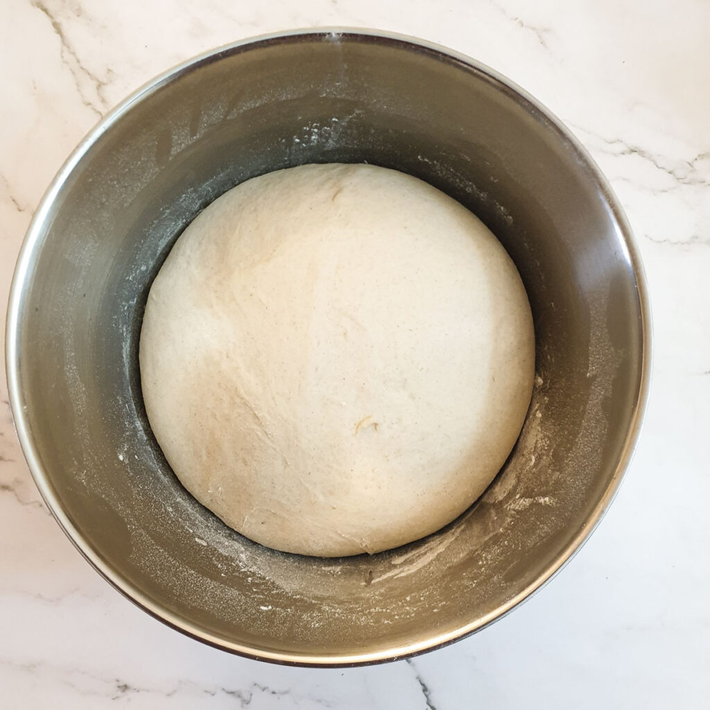 Dough that has risen and doubled in size, in a mixing bowl.