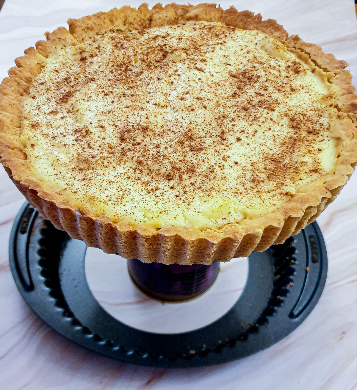 A milk tart being removed from the baking dish.