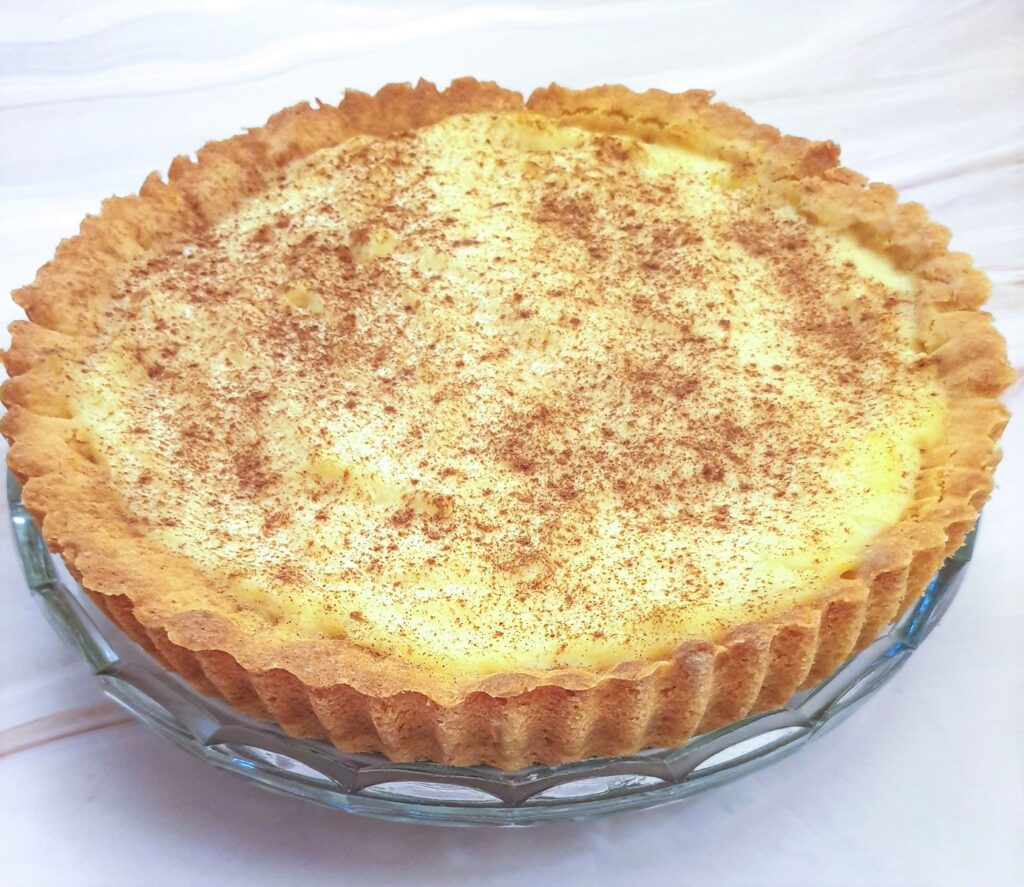 A milk tart on a glass plate.