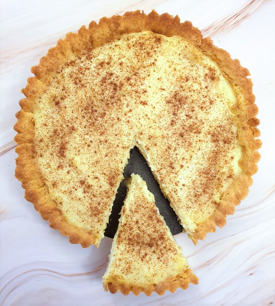Overhead shot of a milk tart with a slice cut out and offset.