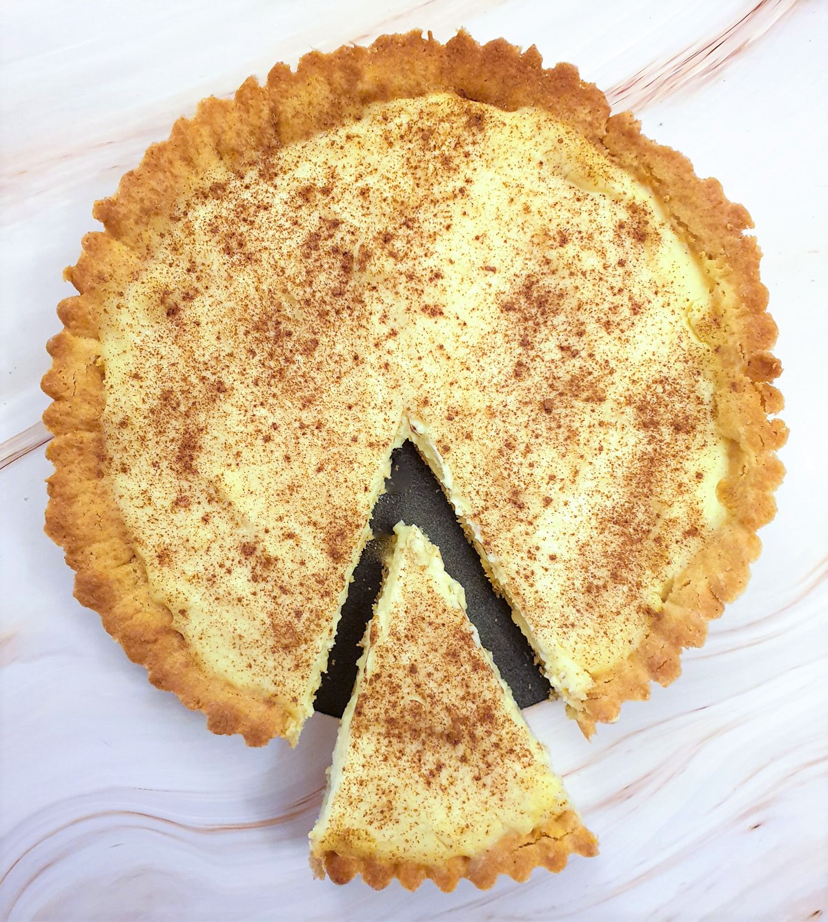 Overhead shot of a milk tart with a slice cut out and offset.