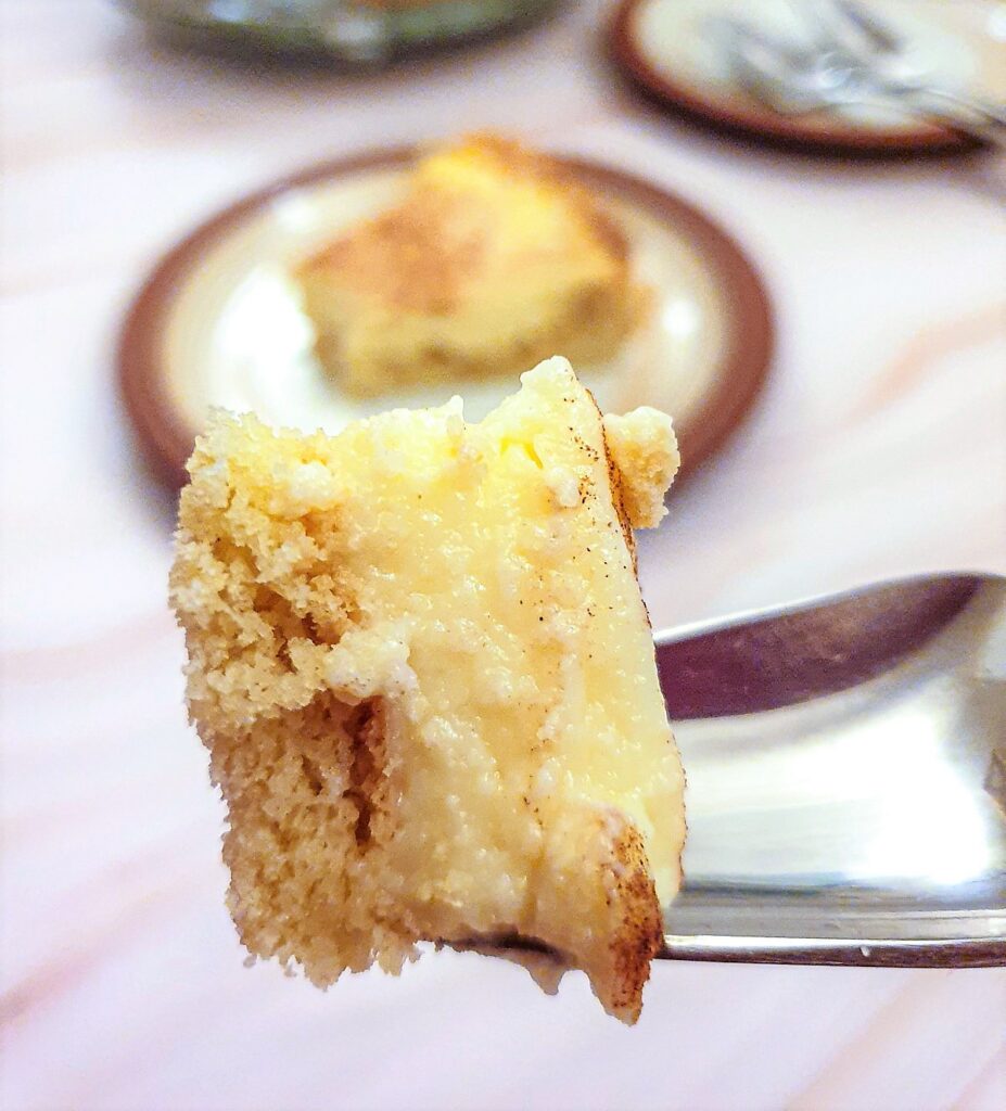 A piece of milk tart on  fork showing the thick creamy texture of the filling.