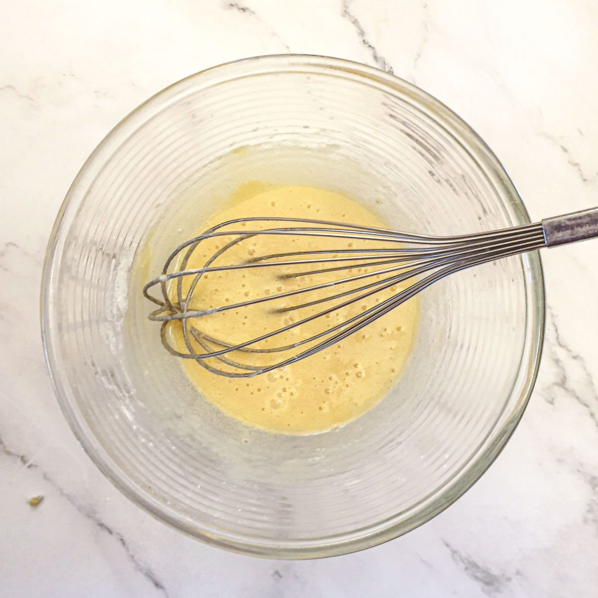 Eggs and flour mixed in a glass bowl.