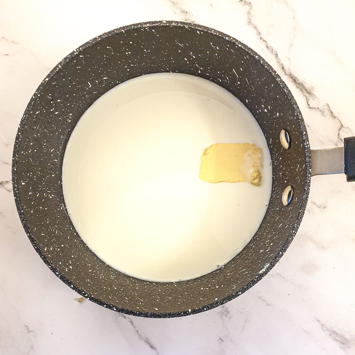 Milk and butter melting in a saucepan.