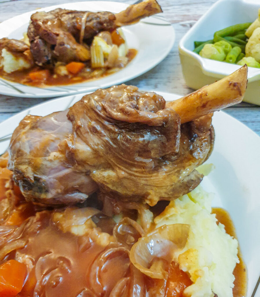 Closeup of a lamb shank on a bed of mashed potatoes.