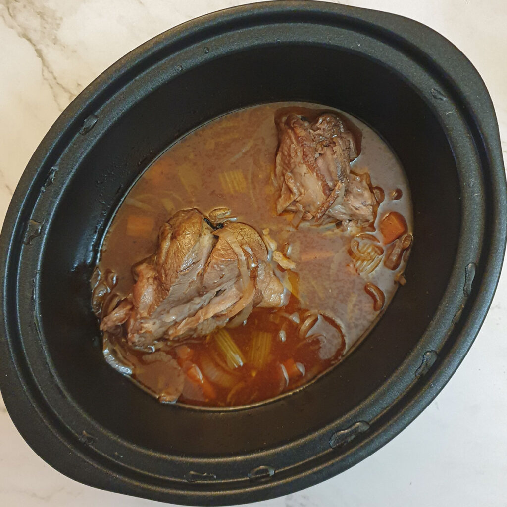 Cooked lamb shanks in a slow-cooker.