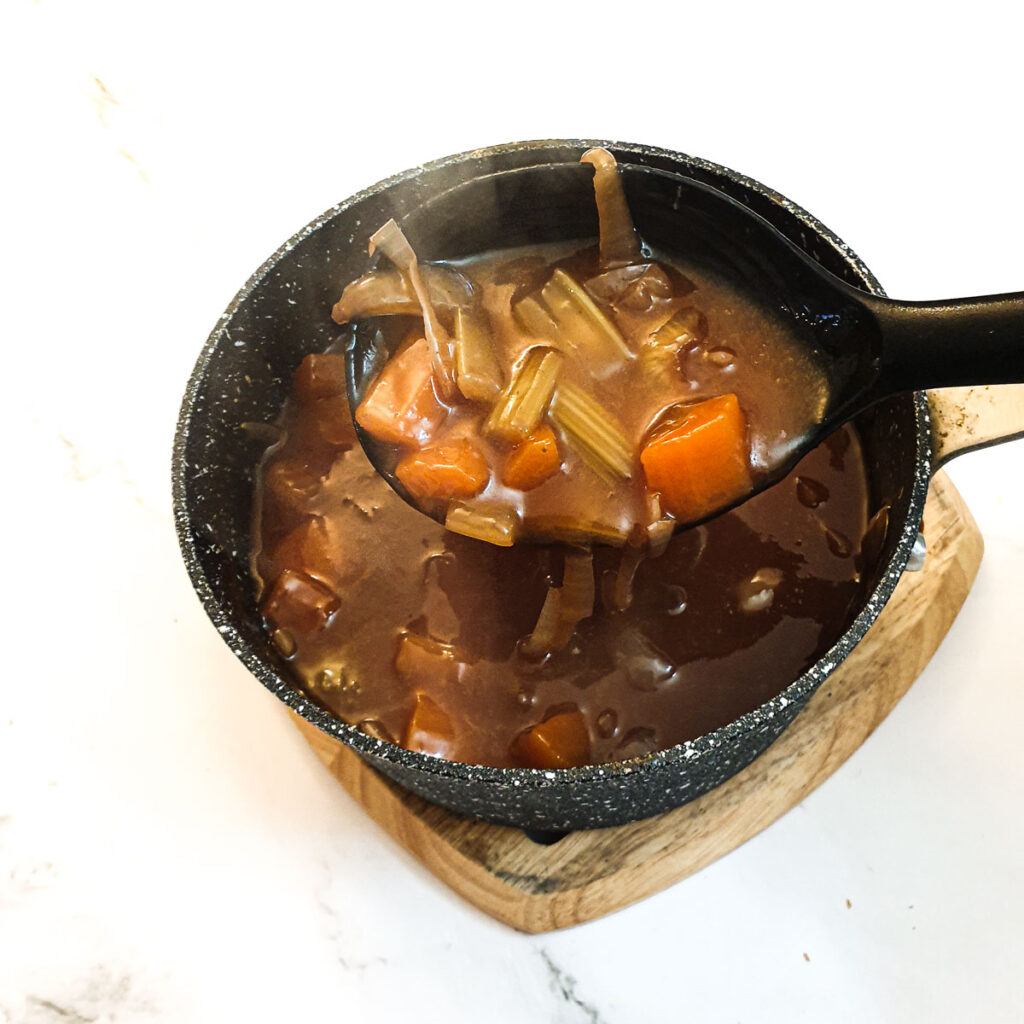 A saucepan containing the vegetables and gravy before being thickened.