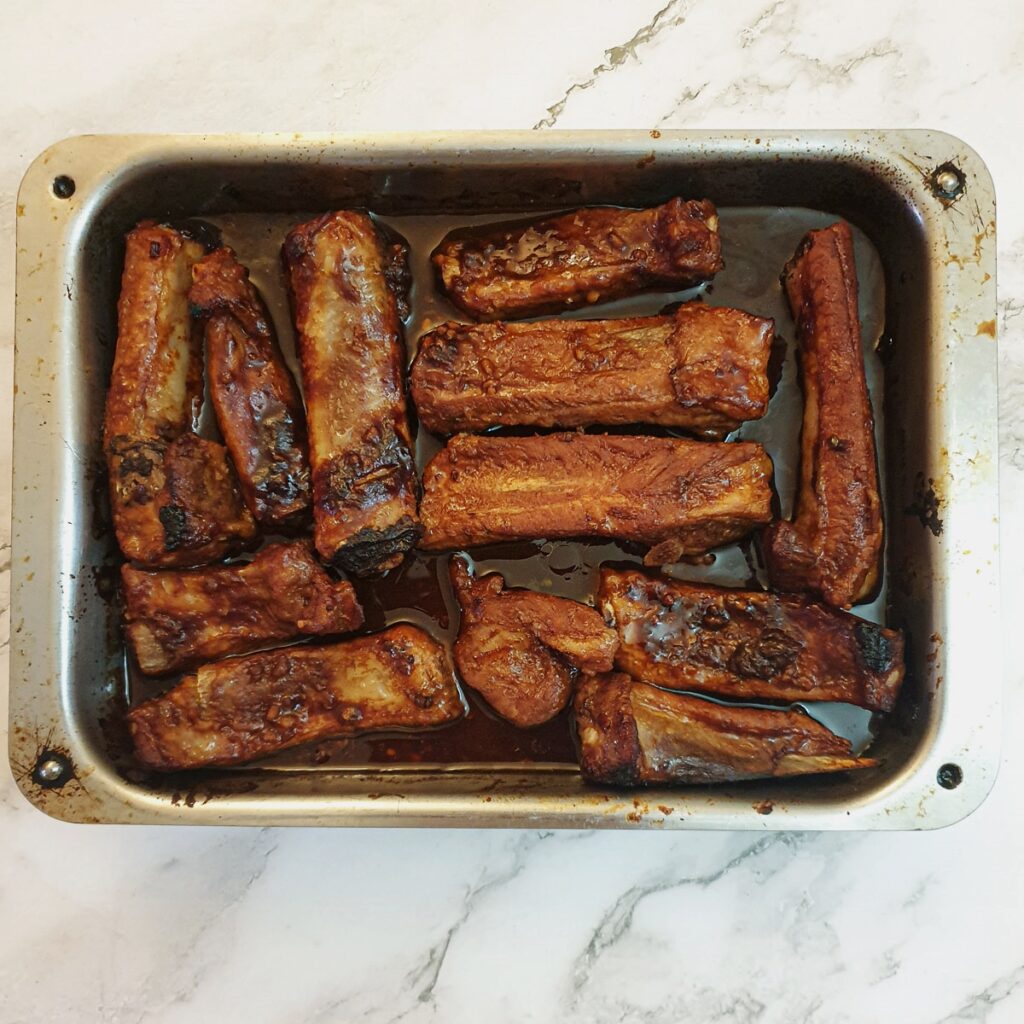 Cooked pork ribs in a metal baking dish.