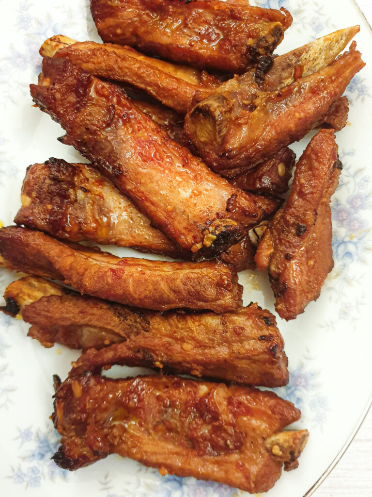 A pile of baked sticky pork ribs on a plate.