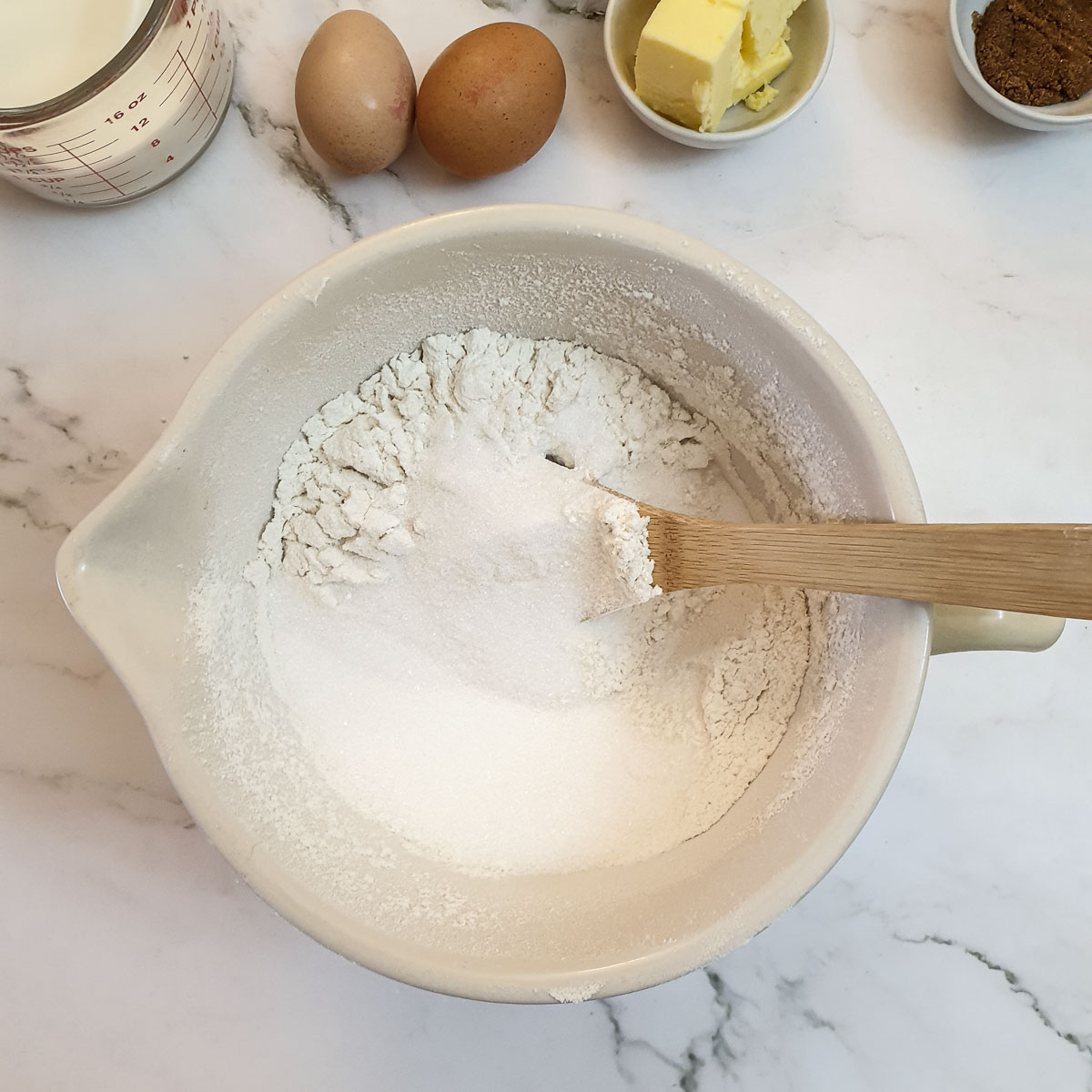 Flour and sugar being mixed in a bowl.