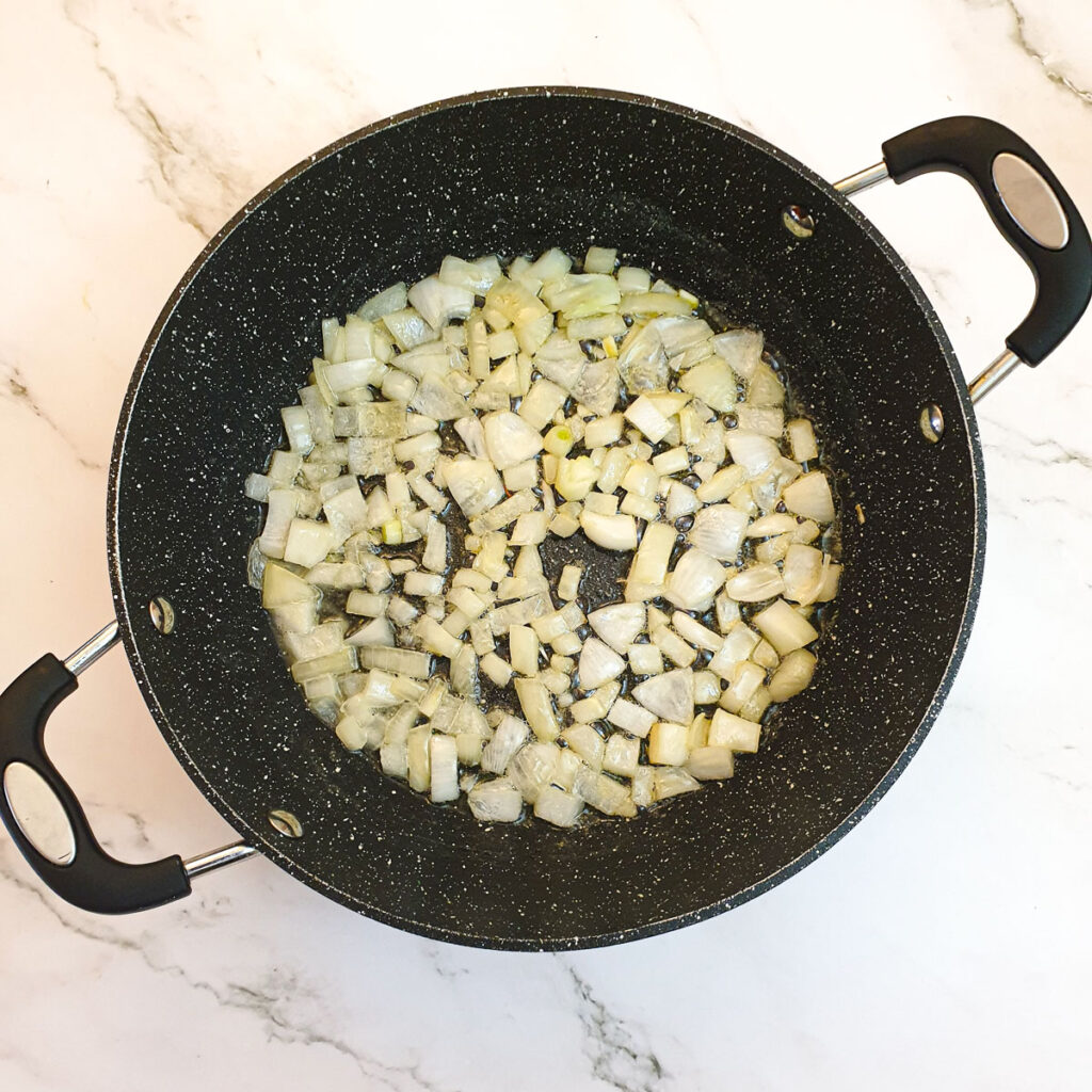 Chopped onions frying in a pan.