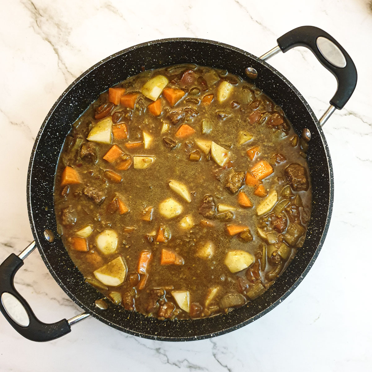 Beef curry simmering in a frying pan.