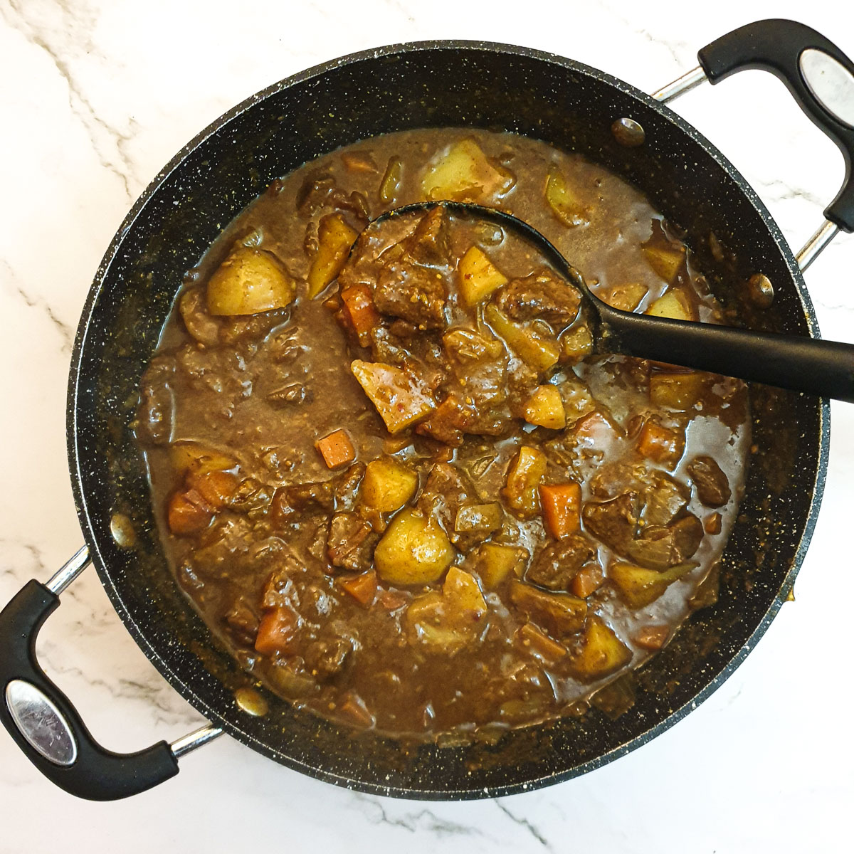 Cooked beef curry in a frying pan.