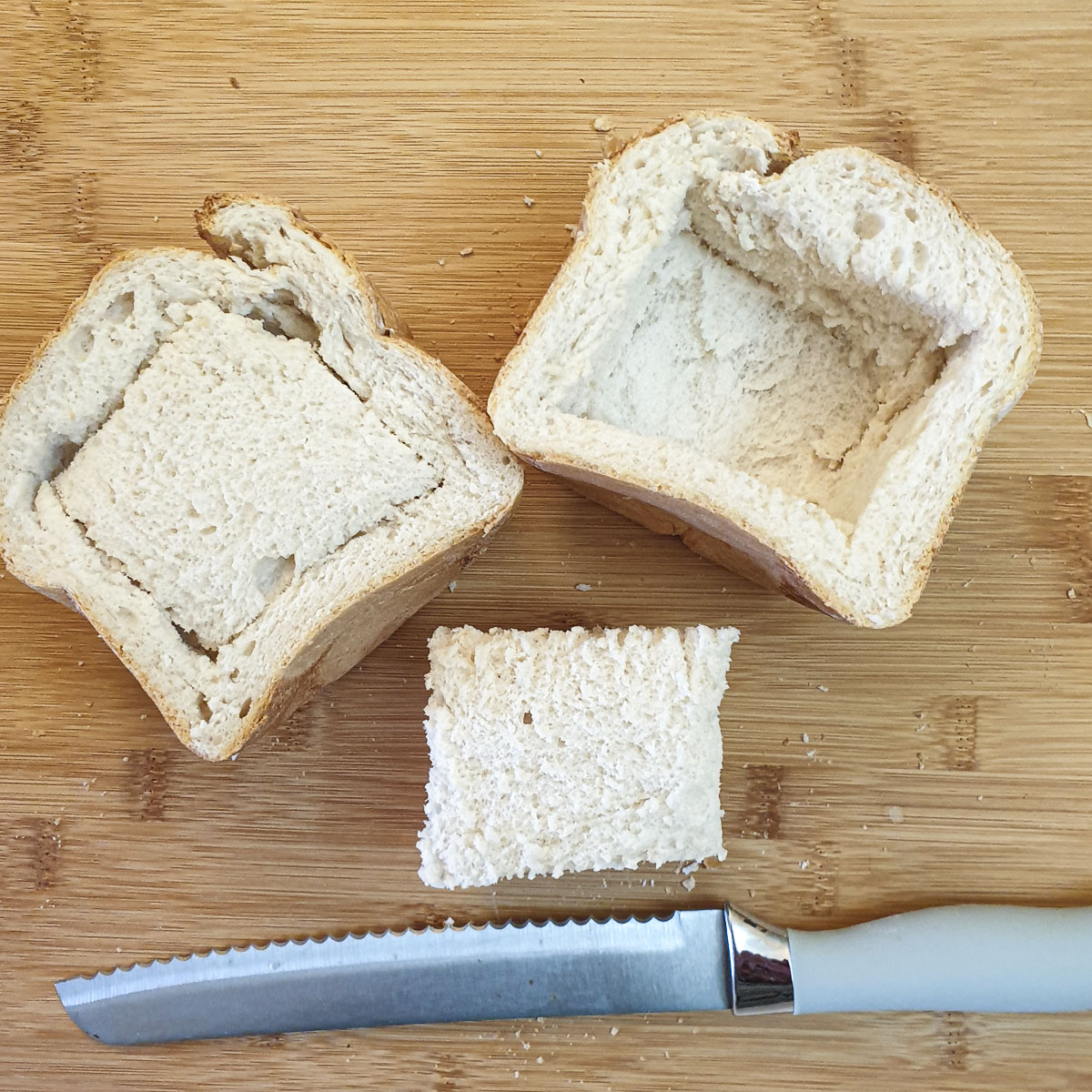 Two halves of a loaf of bread with the centre pieces being removed.