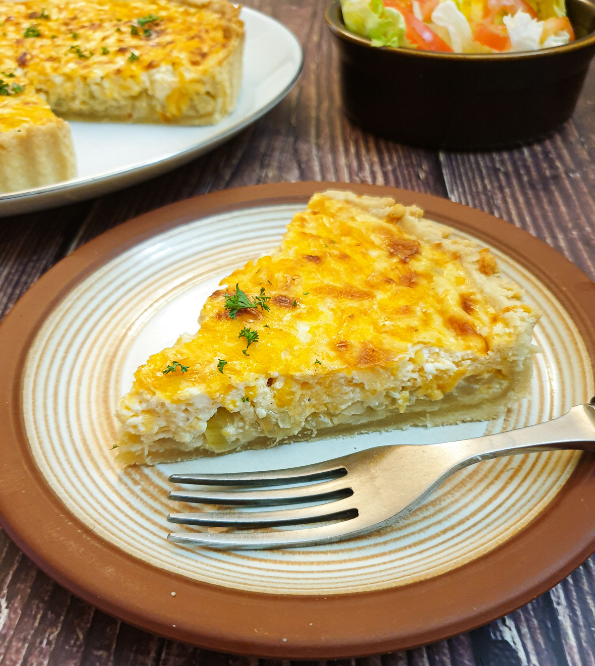 A slice of cheese and onion quiche on a plate.