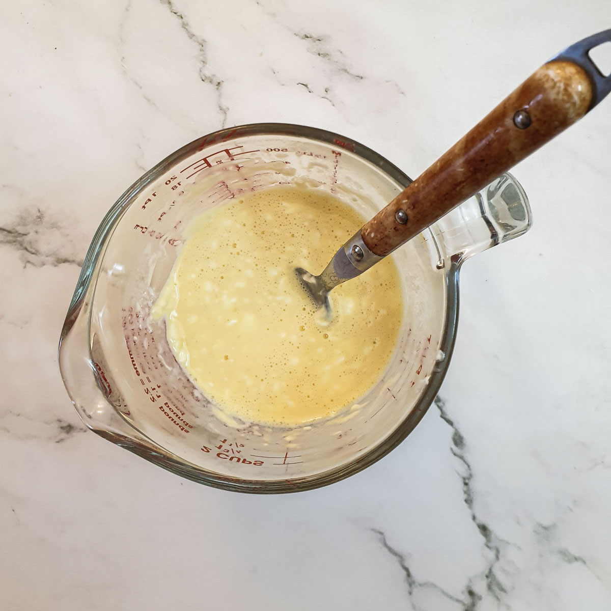 Egg and cream cheese being mixed in a jug.