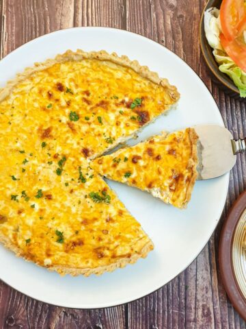 Overhead shot of a cheese and onion quiche with one slice cut out and offseet.