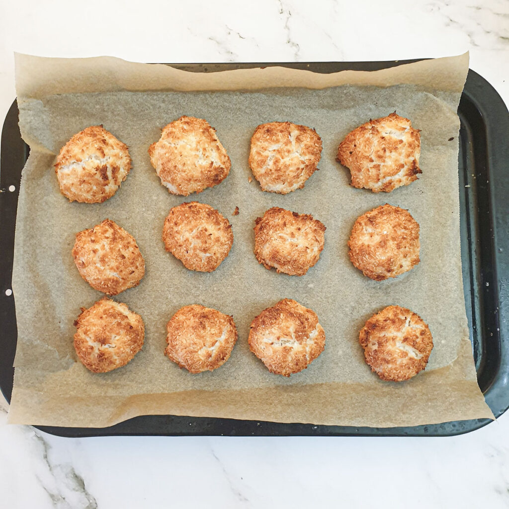 12 baked coconut macaroons on a baking tray.