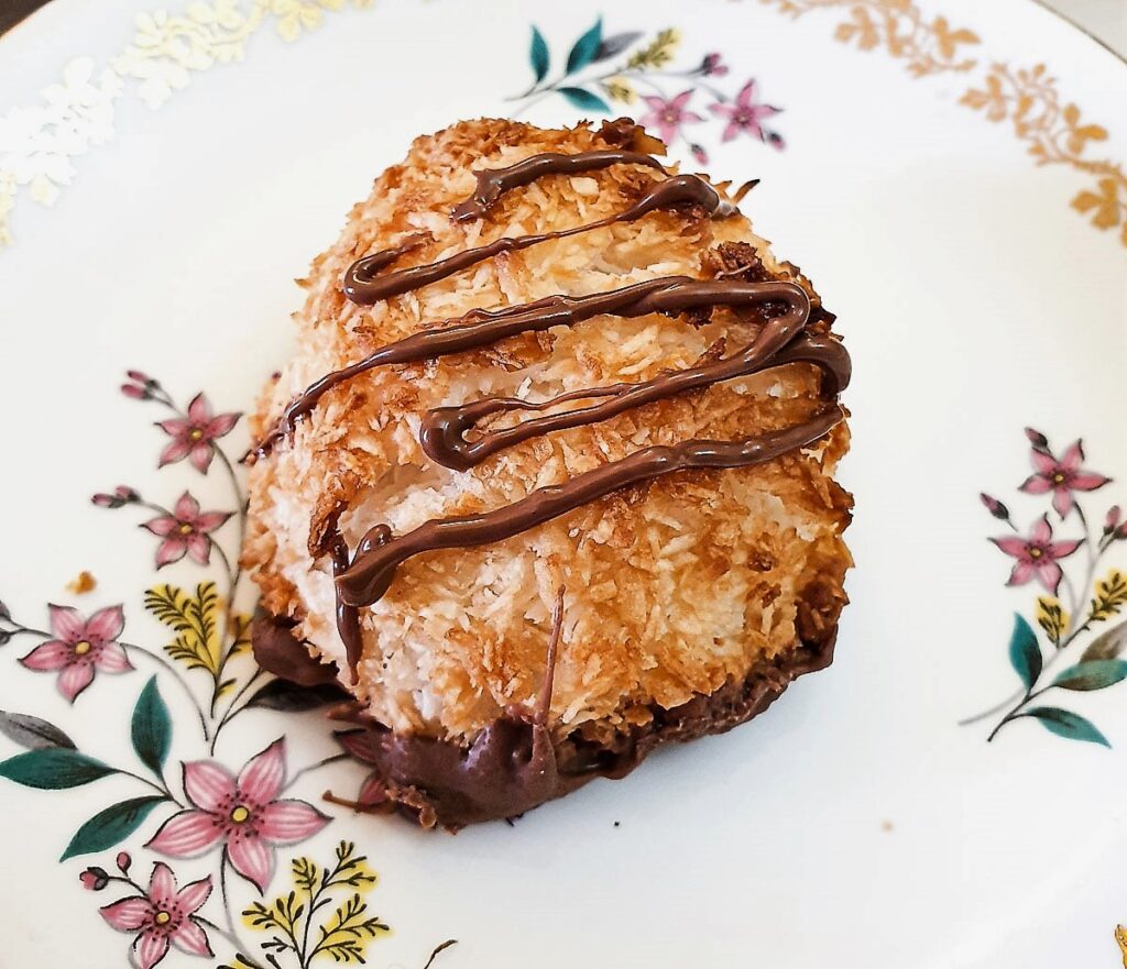 Close up of a coconut macaroon drizzled with chocolate.