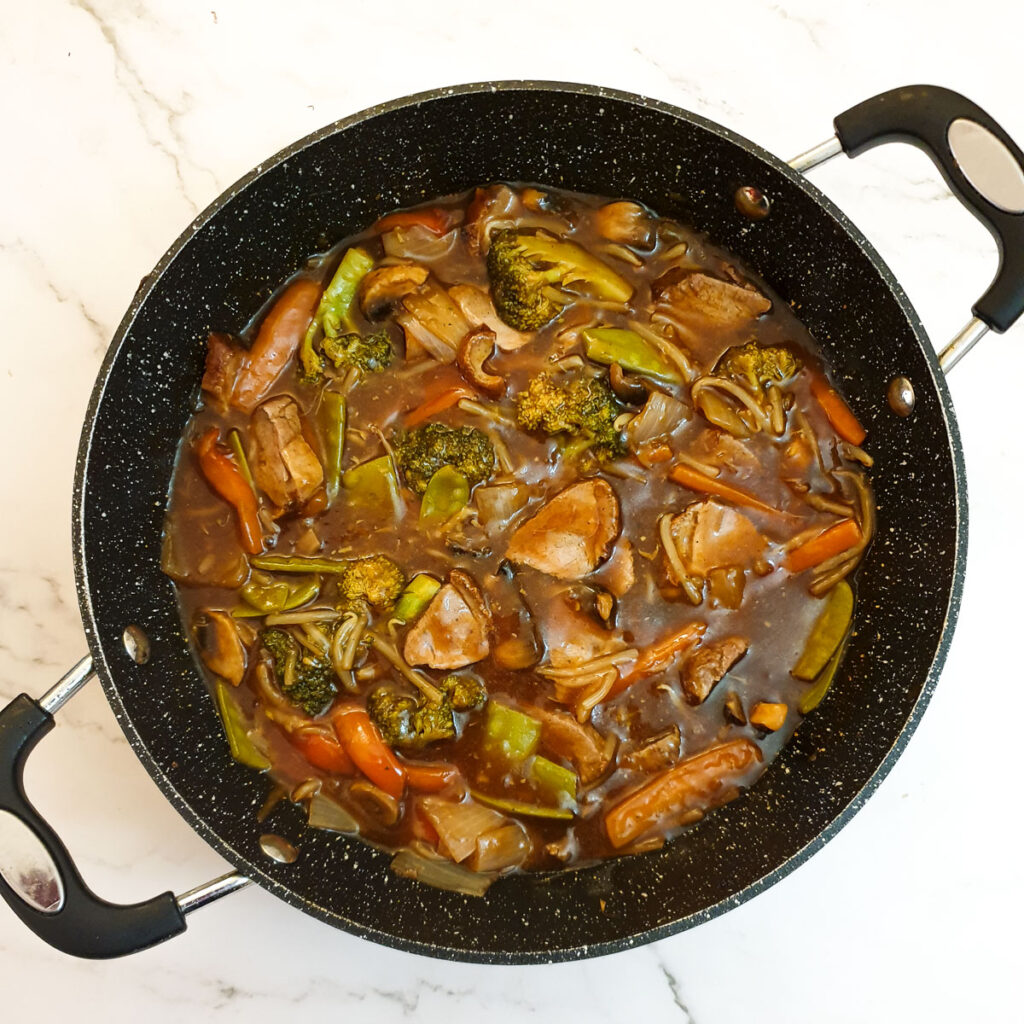 The finished dish of duck in garlic sauce in frying pan.