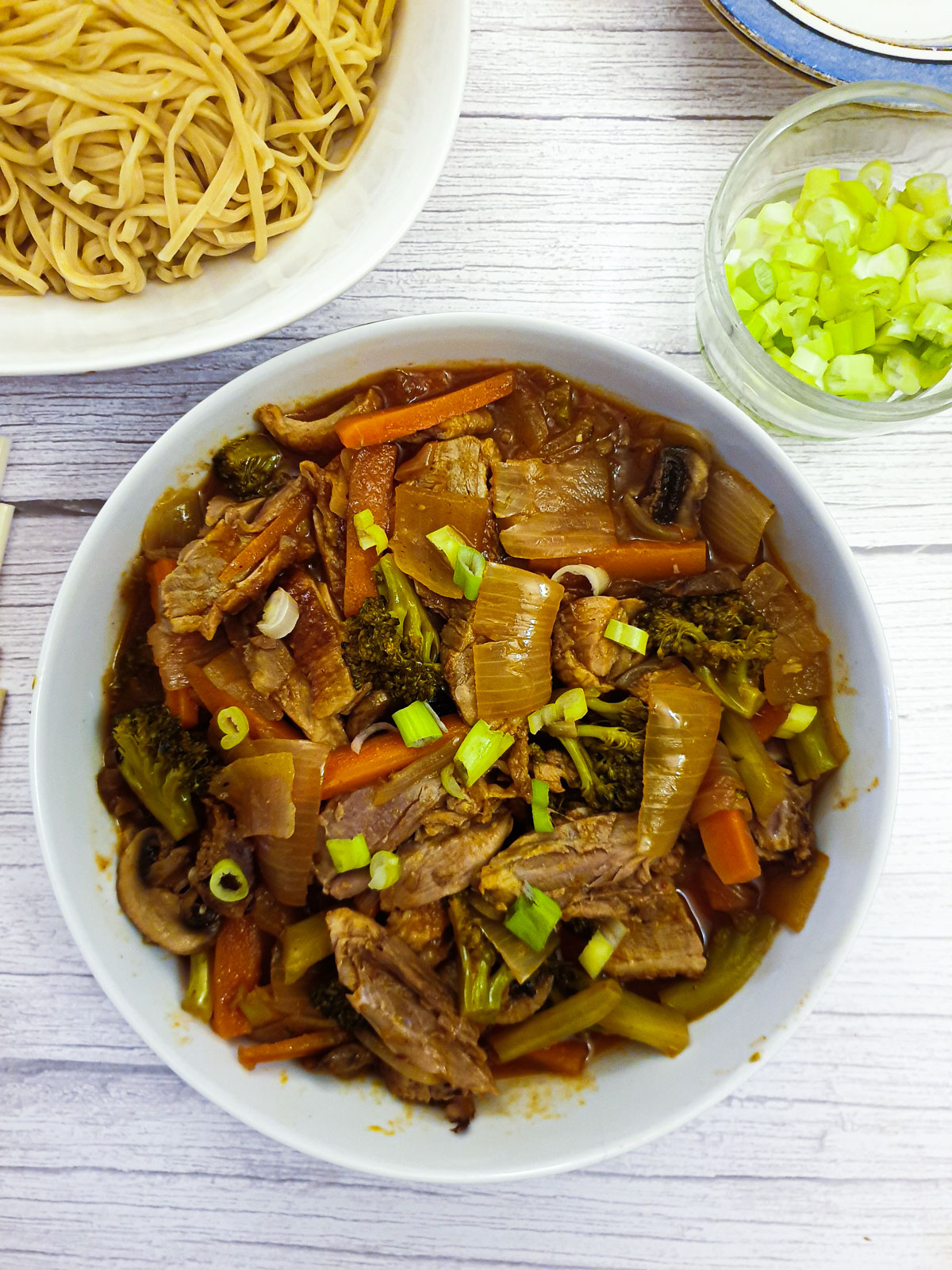 A dish of duck in garlic sauce with vegetables next to a dish of pasta.