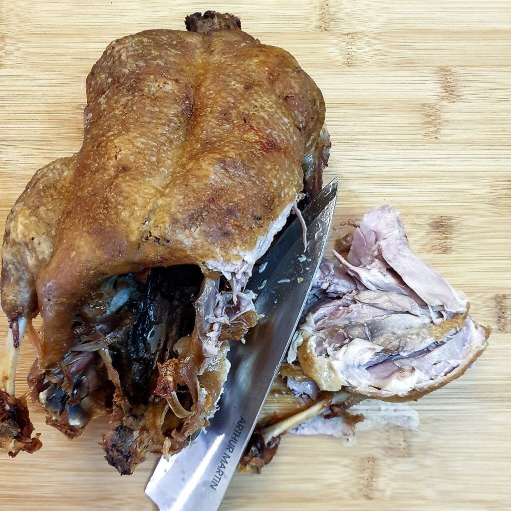 The legs being removed from a roast duck.