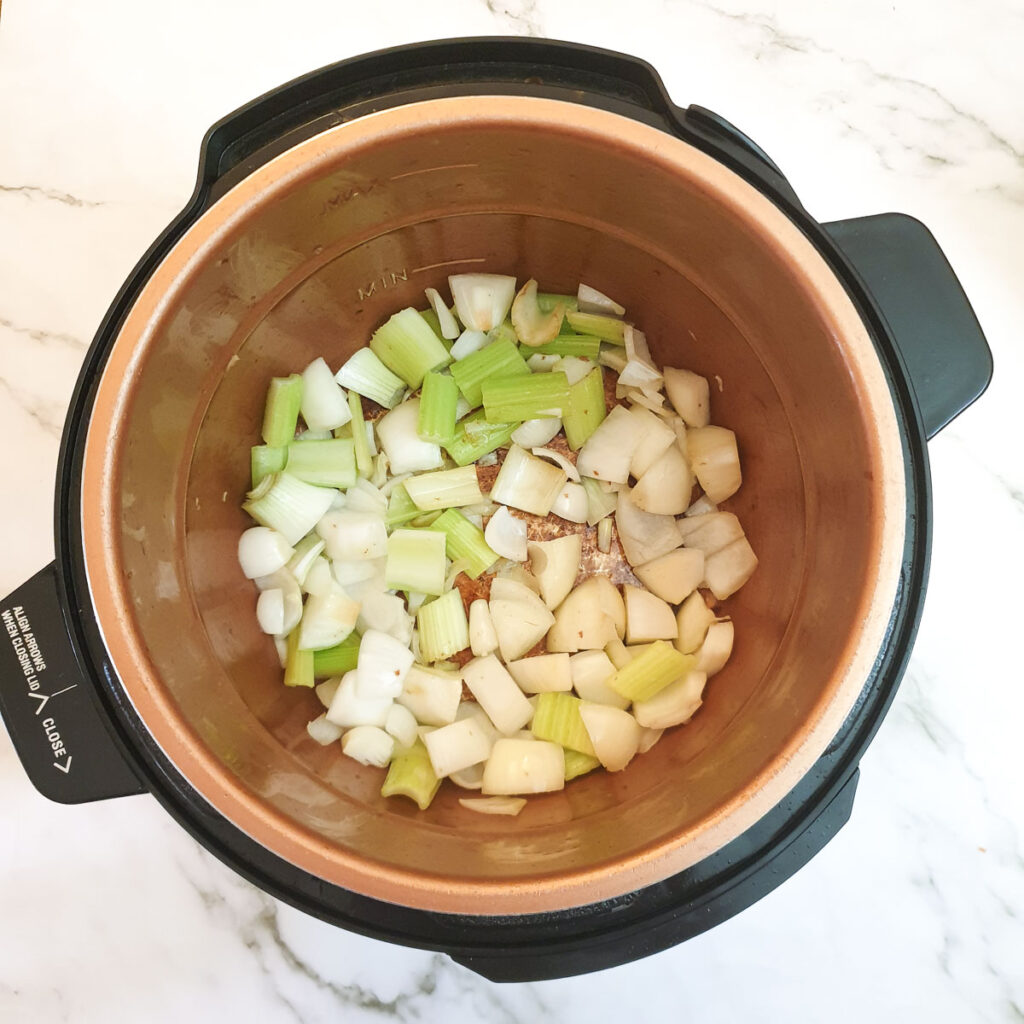 Onions and celery browning in a pressure cooker.