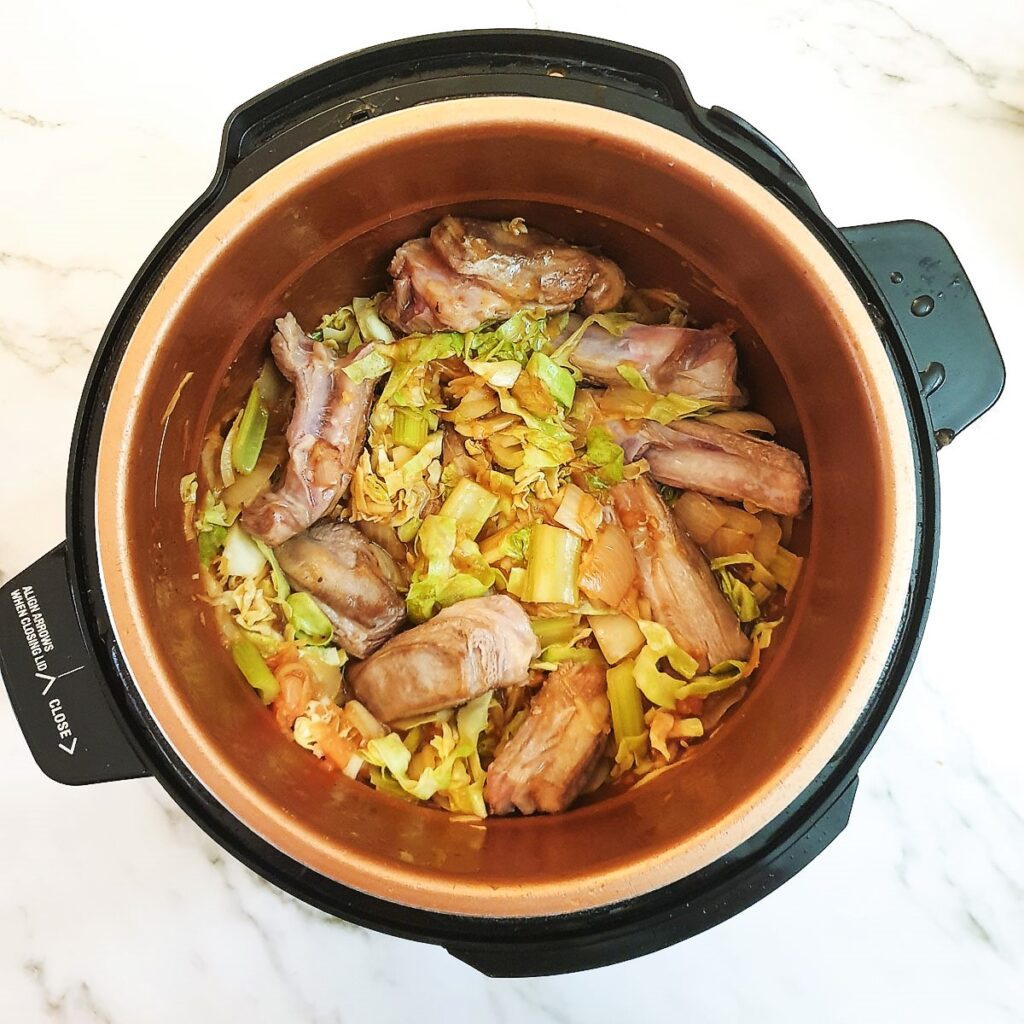 Cabbage, onions, celery and lamb in a pressure cooker, mixed with the stock.