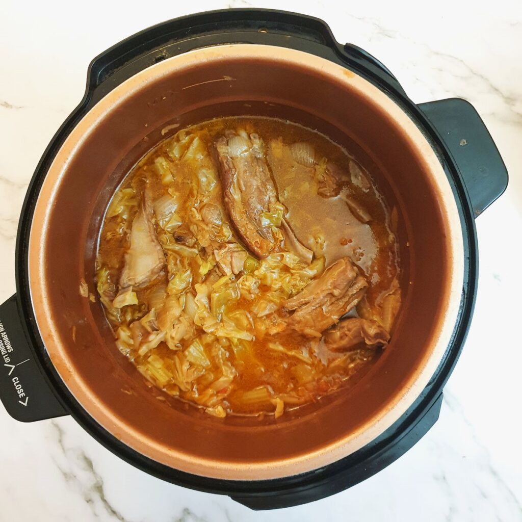 Cooked lamb ribs in vegetables and stock in a pressure cooker.