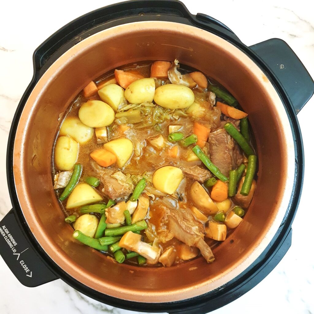 Vegetables added to lamb bredie in a pressure cooker.