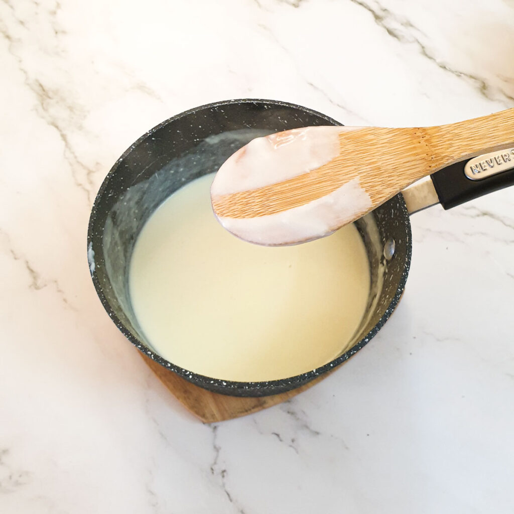 A wooden spoon coated with sauce, showing the thickness of the sauce.