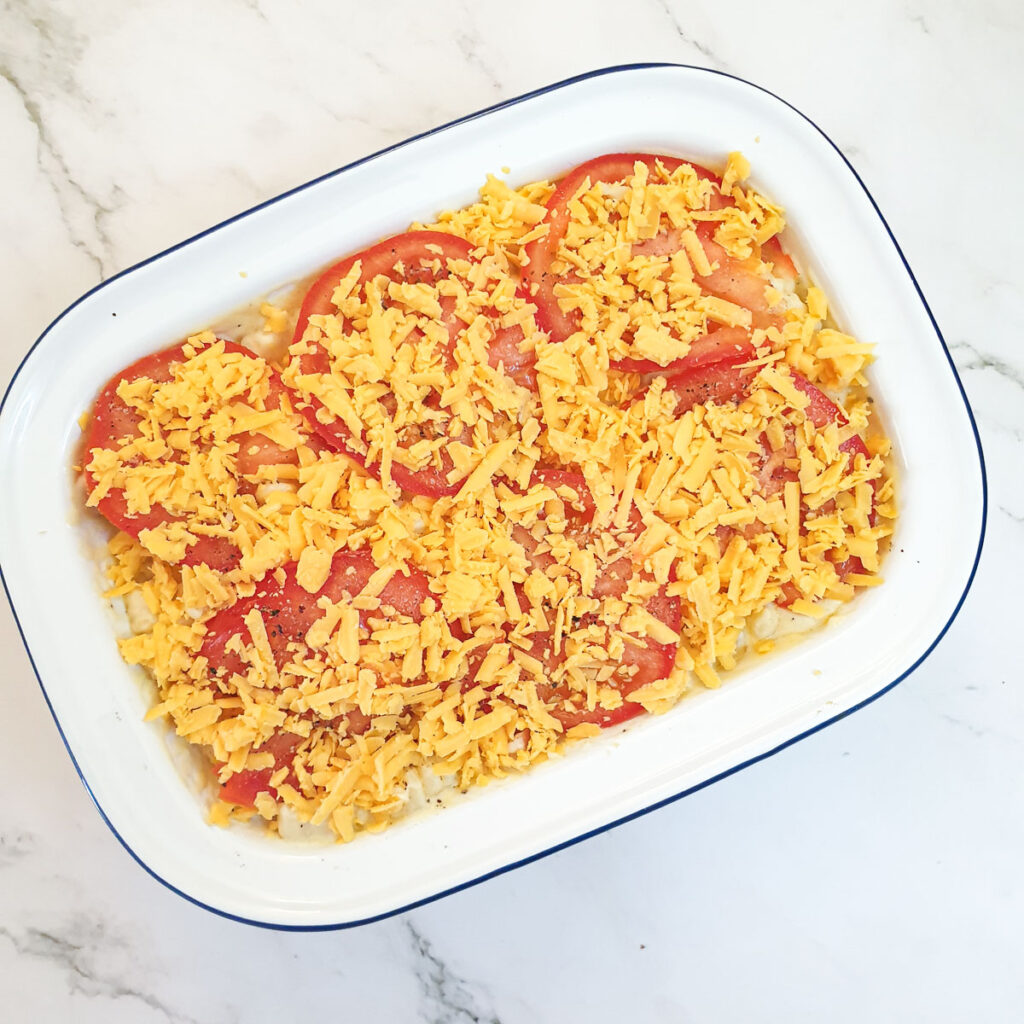 Macaroni cheese topped with sliced tomatoes and grated cheese.