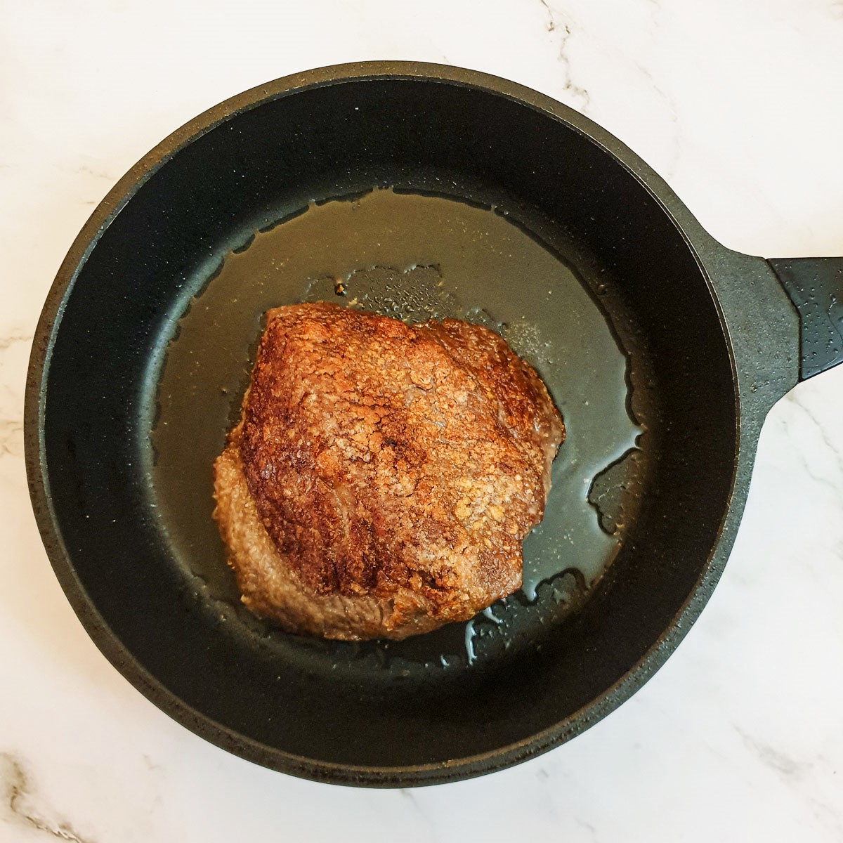 A small beef joint browning in a frying pan.