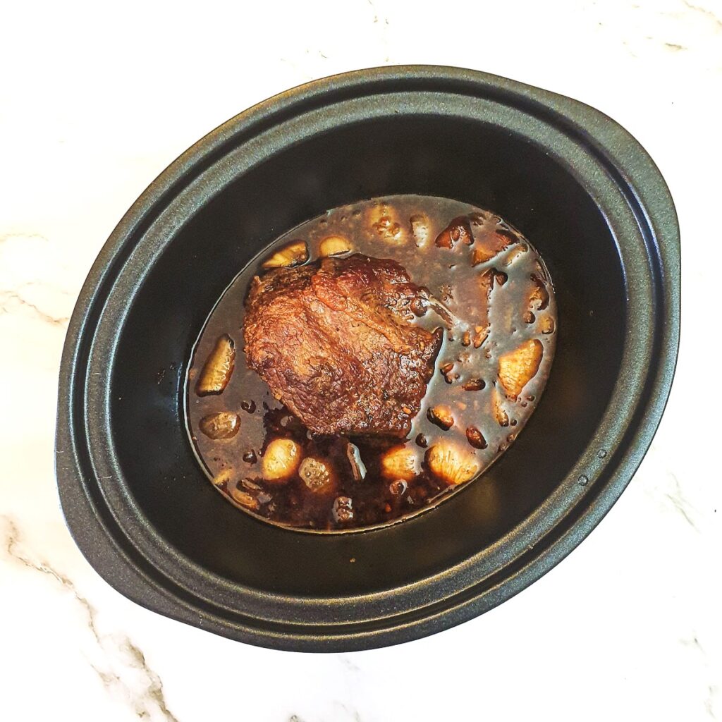 A cooked beef joint in a slow cooker.