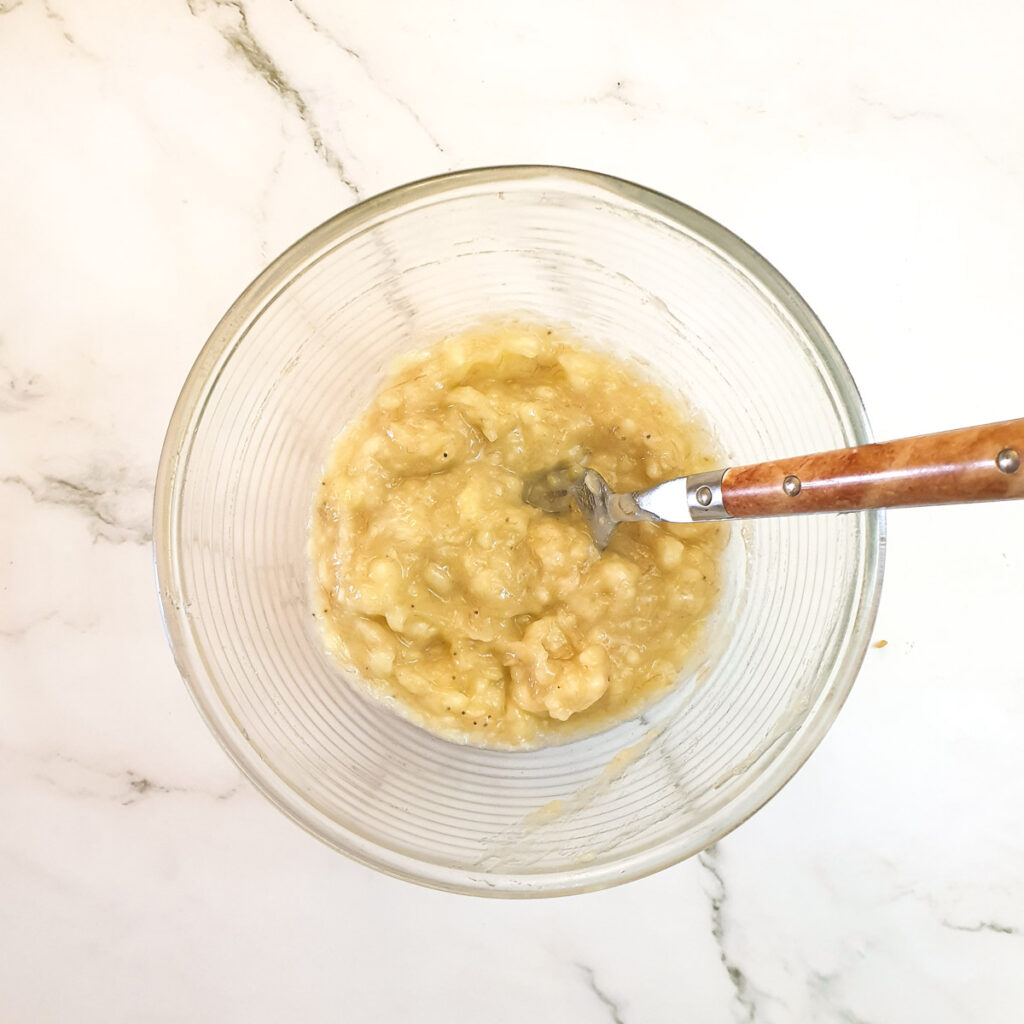 Mashed bananas in a bowl with a fork.