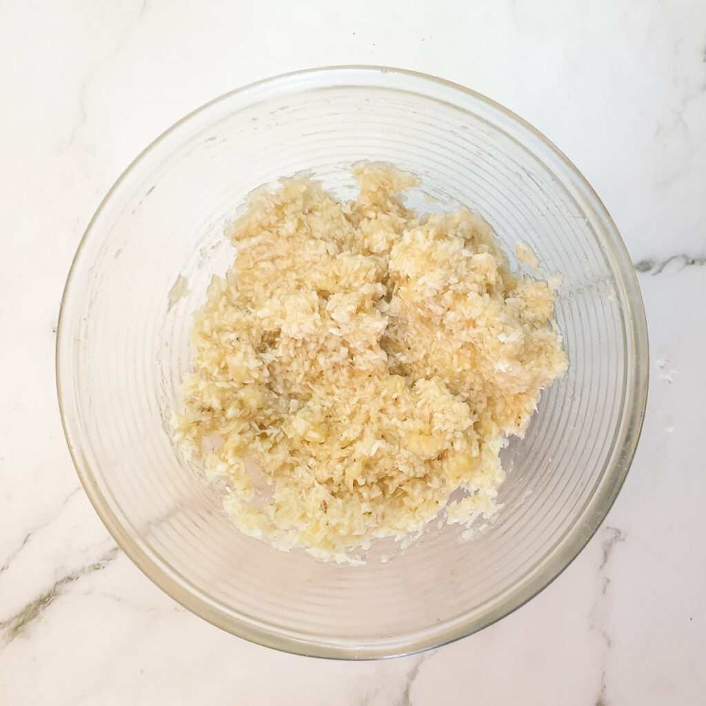 A bowl of mashed bananas mixed with desiccated coconut.