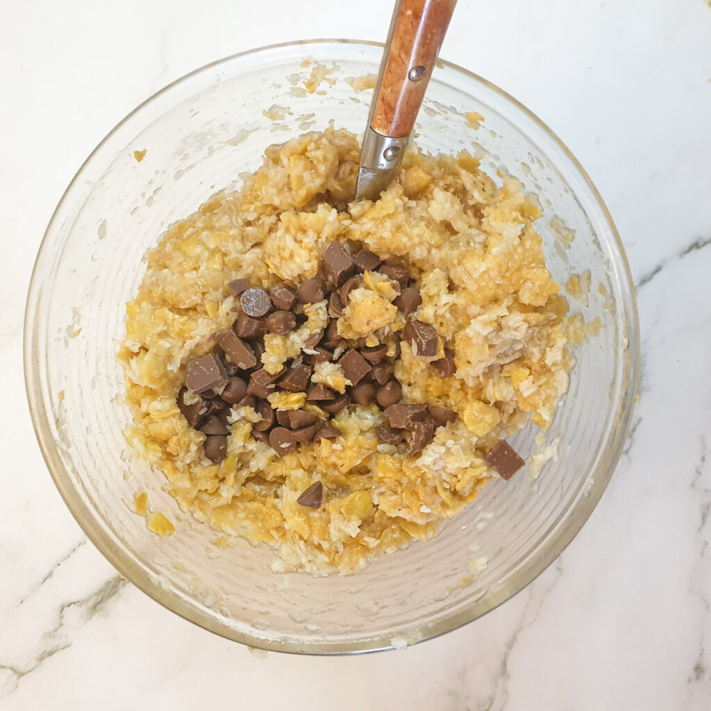 Chocolate chips being added to the banana cake mixture.