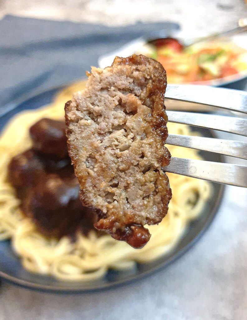 Close up of half a meatball on a fork, showing the texture.