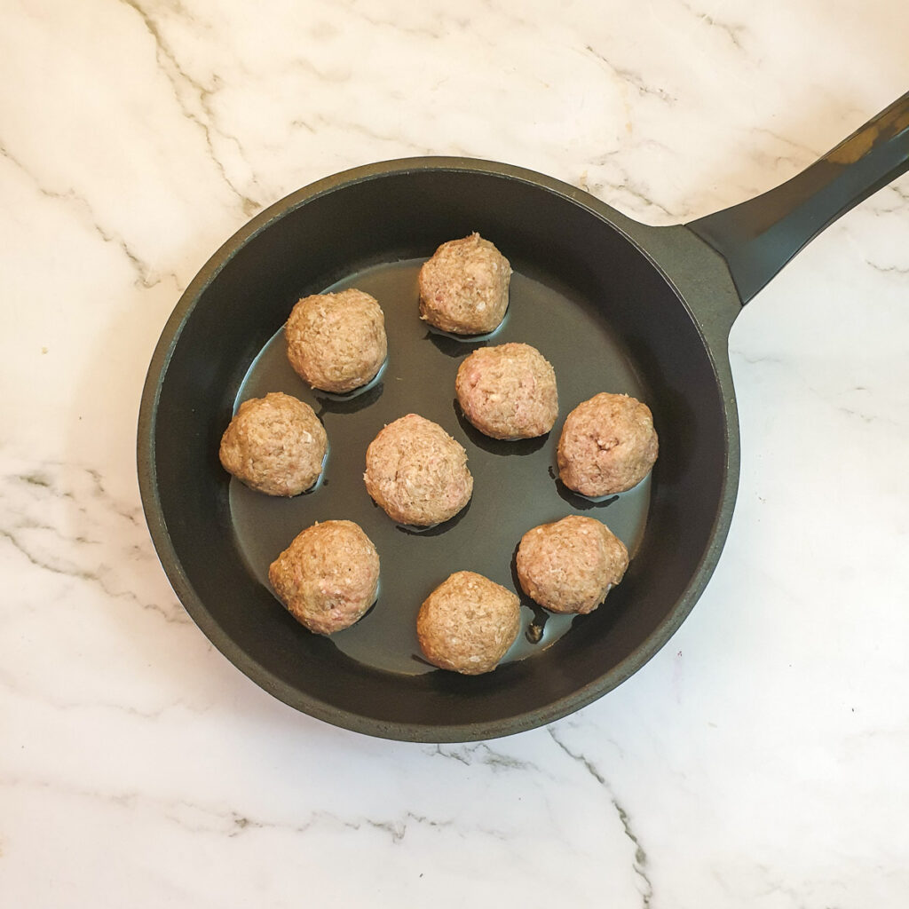 9 meatballs in a frying pan.