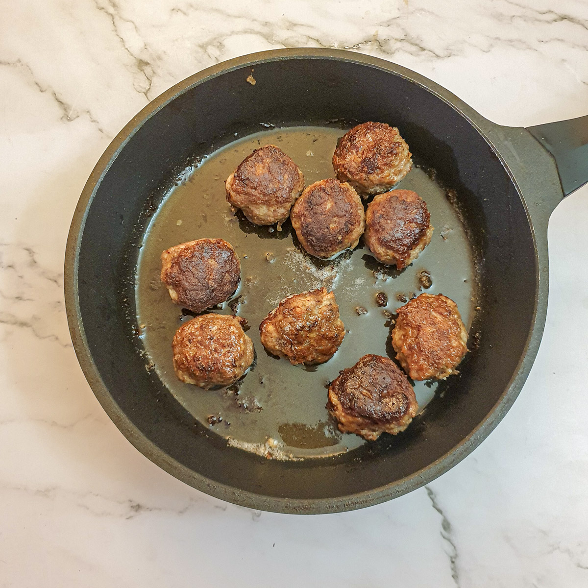 Browned meatballs in a frying pan.
