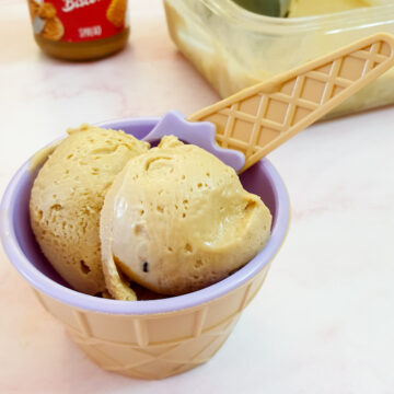 2 scoops of biscoff ice cream in a plastic bowl with a spoon.