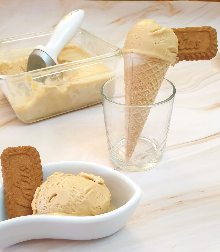 Biscoff ice-cream in an ice cream cone next to a dish of ice cream.