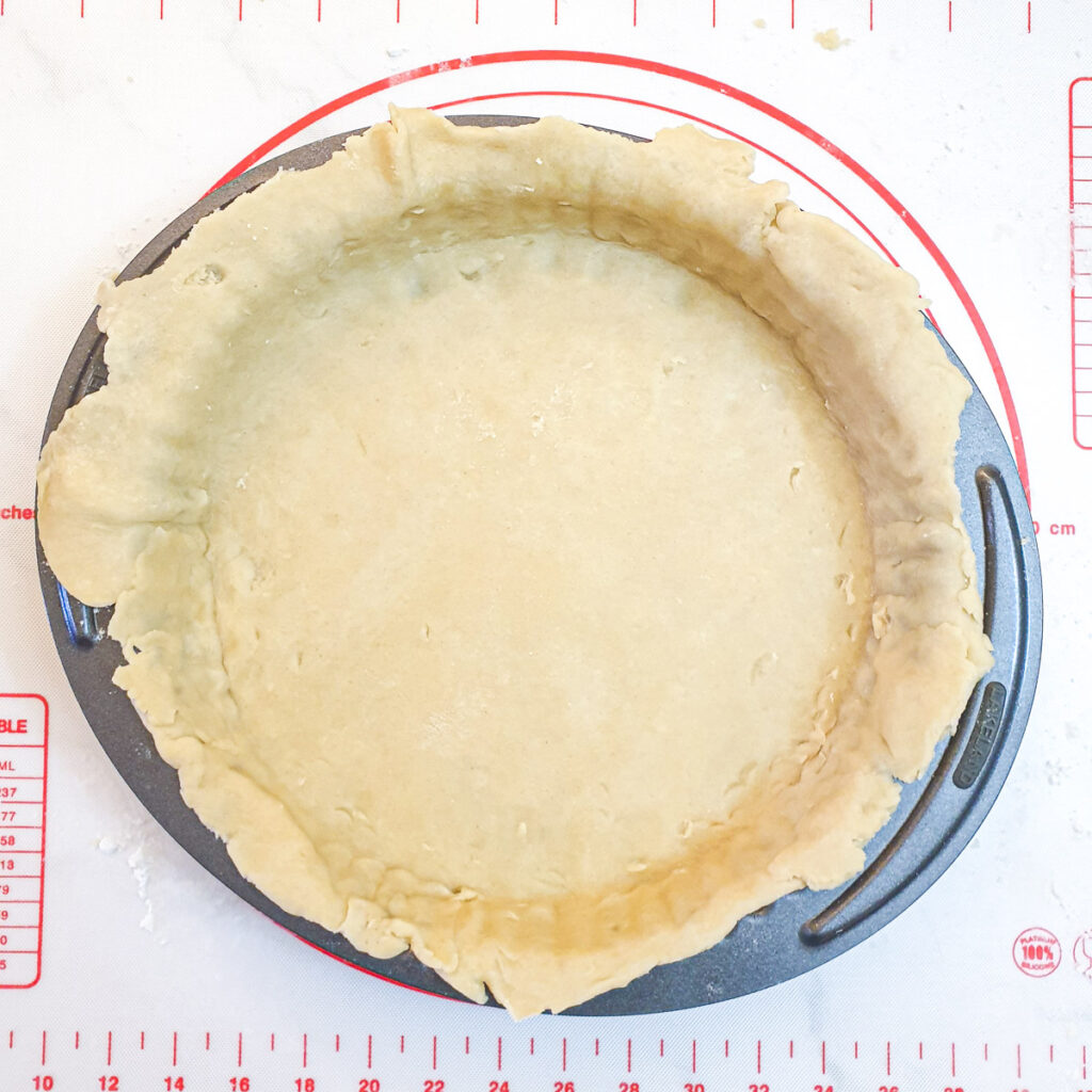 A round baking dish lined with pastry.