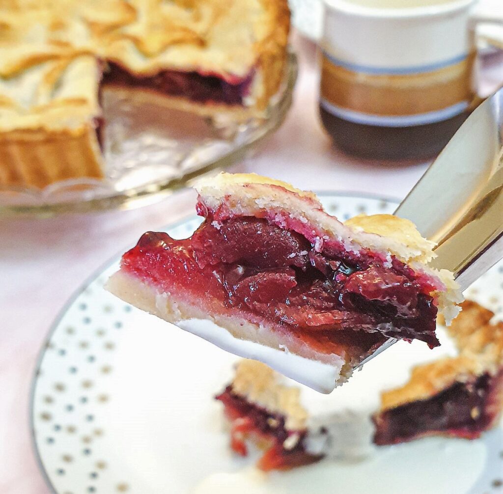 Close up of a piece of blackberry and apple pie on a fork.