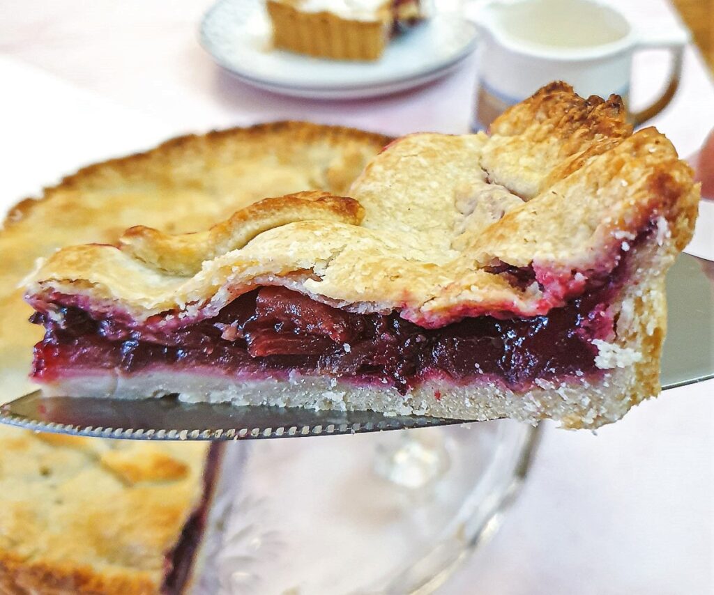 A slice of apple and blackberry pie being lifted from the serving dish.