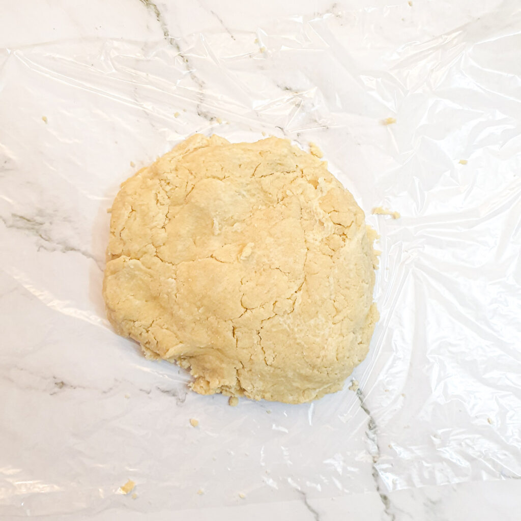 A ball of pastry on a sheet of plastic wrap.