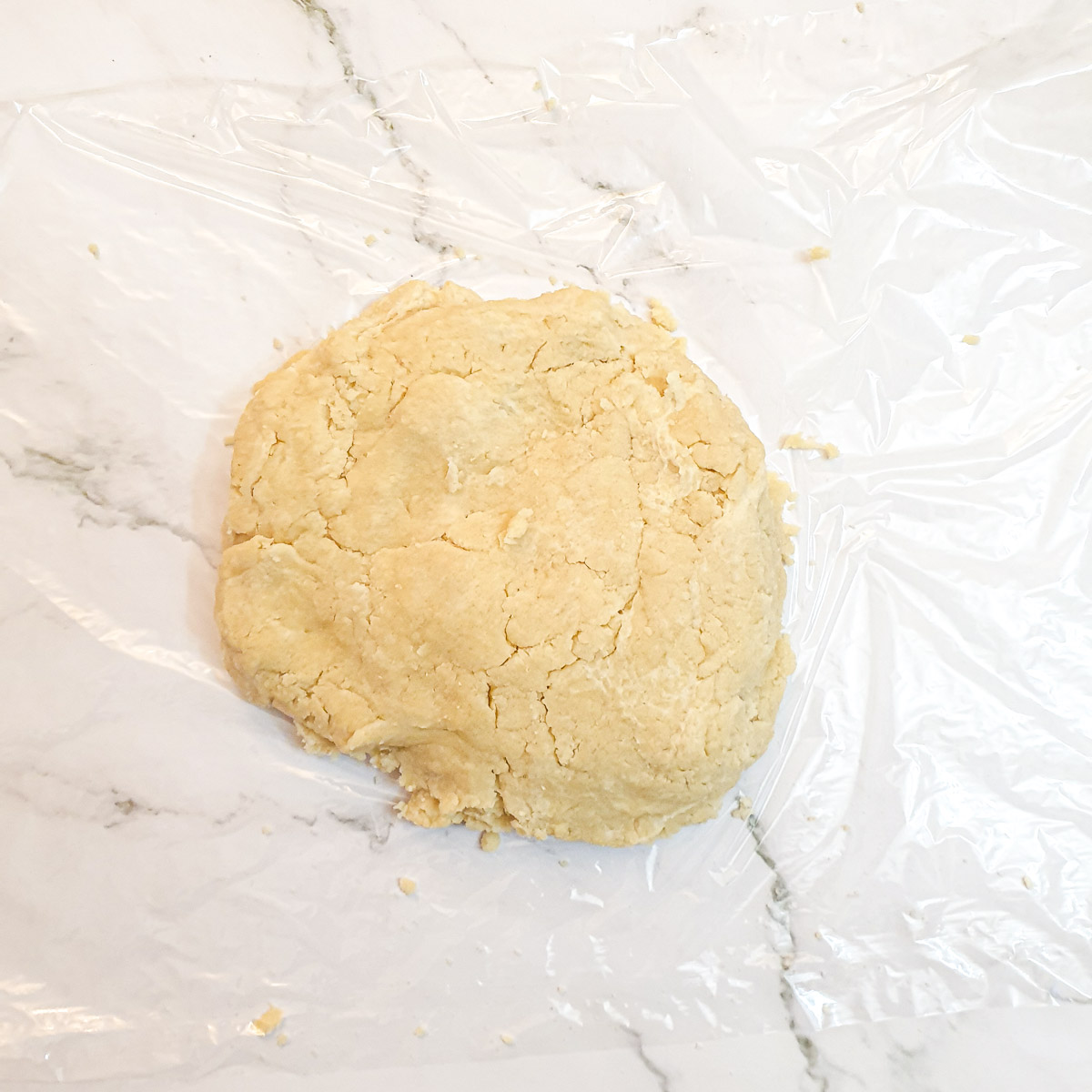 A ball of pastry on a sheet of plastic wrap.