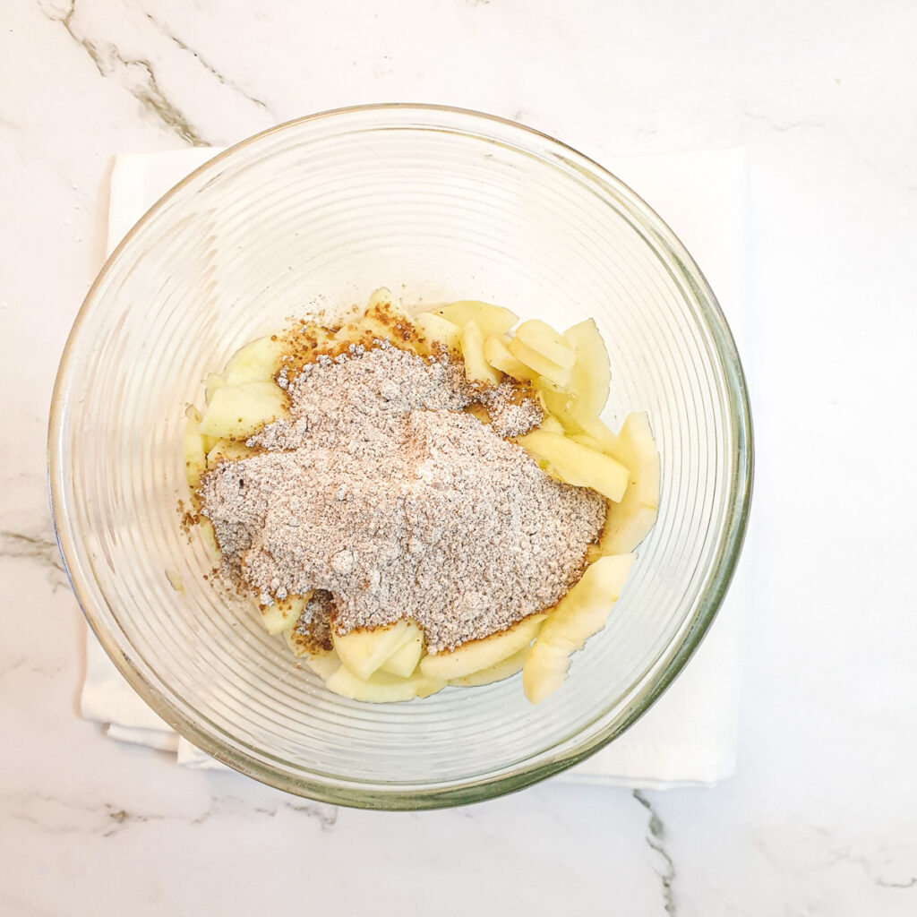 Apples in a bowl with sugar and cornflour.