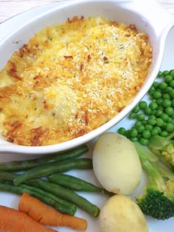 Overhead shot of a dish of cod mornay on a plate with vegetables.